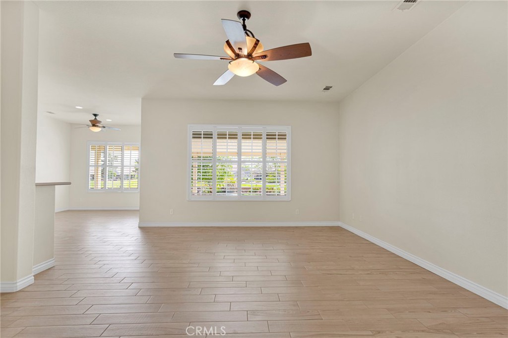 10429 Lanigan Road Apple Valley, CA 92308 - Photo 13 of 41 an empty room with wooden floor chandelier fan and windows