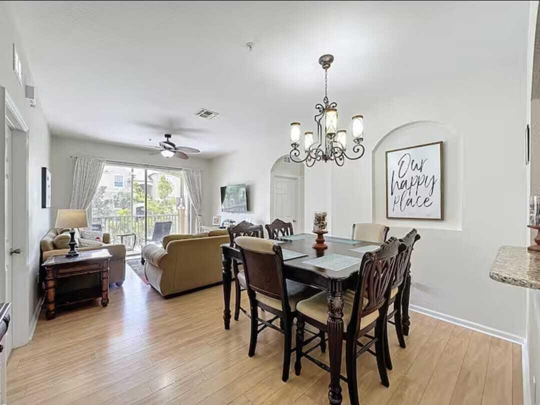 2784 Almaton Loop, Unit 301 Kissimmee, FL 34747 - Photo 6 of 37 a dining room with wooden floor a chandelier a wooden table and chairs