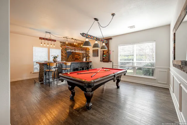 a room with furniture pool table wooden floor and windows
