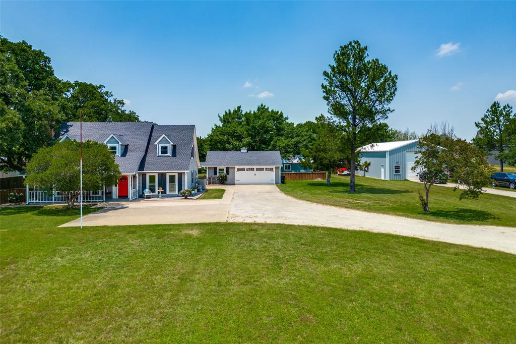 a view of a house with a big yard potted plants and large tree