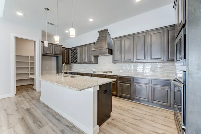 a kitchen with kitchen island granite countertop a sink cabinets and stainless steel appliances