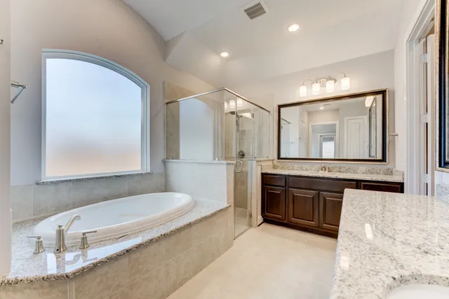 a bathroom with a tub a double vanity sink and a mirror