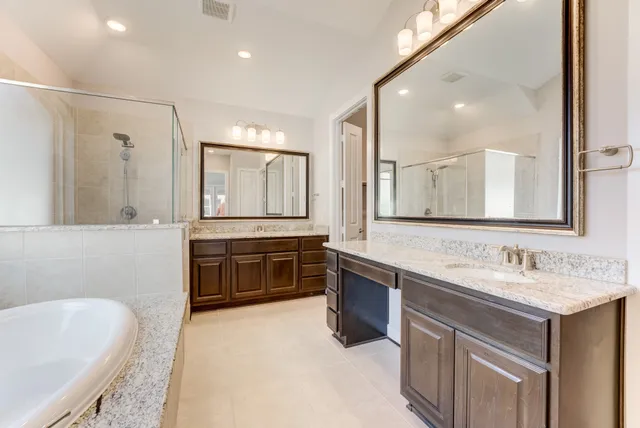 a spacious bathroom with a tub double sink and mirror