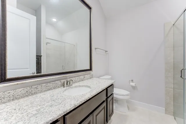 a bathroom with a granite countertop sink a toilet and a mirror