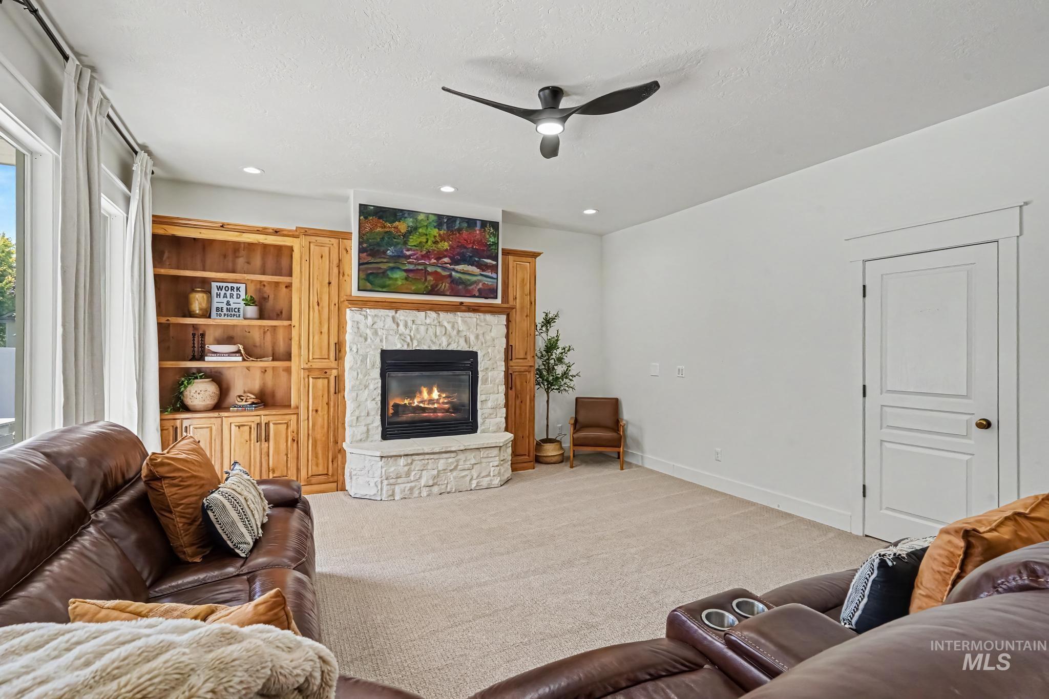 2340 South Alaska Way Meridian, ID 83642 - Photo 11 of 48 Built-in wood cabinetry with shelving, stone-surround fireplace, and a contemporary ceiling fan