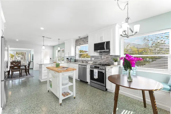 a open kitchen with stainless steel appliances granite countertop a stove top oven a sink dishwasher and a dining table with wooden floor