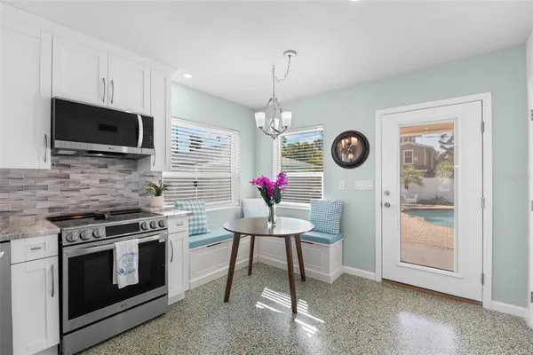 a kitchen with stainless steel appliances granite countertop a stove top oven a sink dishwasher a dining table and chairs with wooden floor