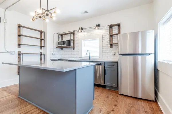 a kitchen with stainless steel appliances a refrigerator a sink and white cabinets