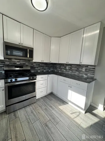 a kitchen with granite countertop a stove a sink and a microwave