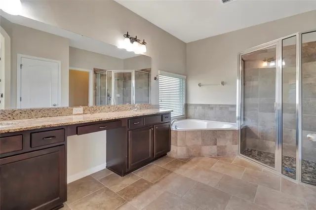 a bathroom with a granite countertop double vanity and a mirror