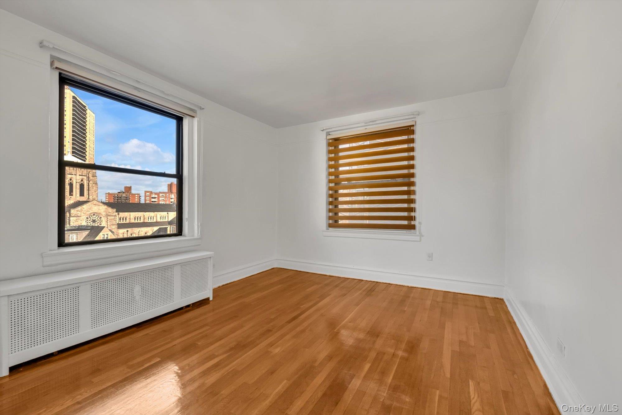 72-34 Austin Street, Unit F10 Queens, NY 11375 - Photo 11 of 15 Unfurnished room featuring radiator heating unit, light wood-style flooring, and a city view