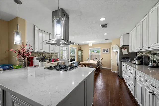 a kitchen with stainless steel appliances kitchen island granite countertop a stove a refrigerator a sink dishwasher and white cabinets with wooden floor