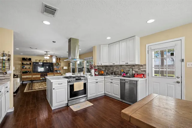 a kitchen with a stove and white cabinets with wooden floors