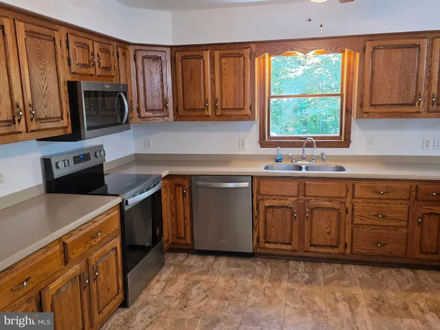 a kitchen with stainless steel appliances granite countertop a sink a stove a microwave a refrigerator and cabinets