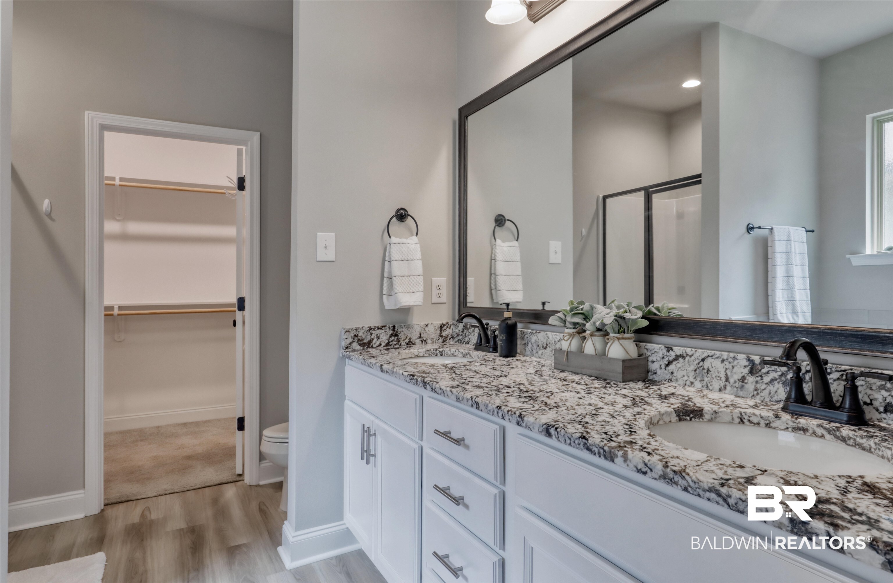987 Gibson Court Foley, AL 36535 - Photo 18 of 34 Bathroom featuring a sink, double vanity, a stall shower, and wood finished floors