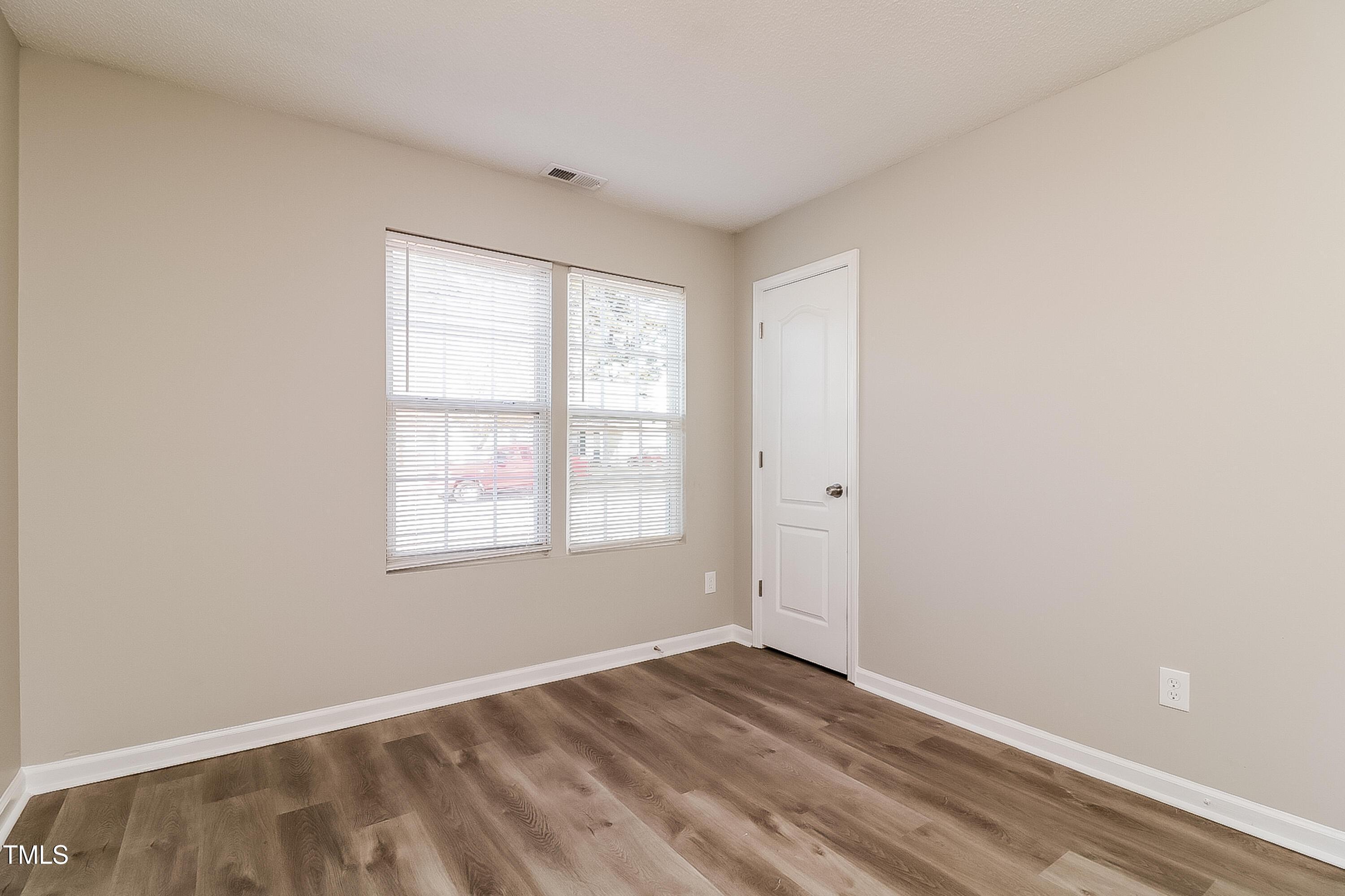 2933 Trassacks Drive Raleigh, NC 27610 - Photo 13 of 17 an empty room with wooden floor and windows