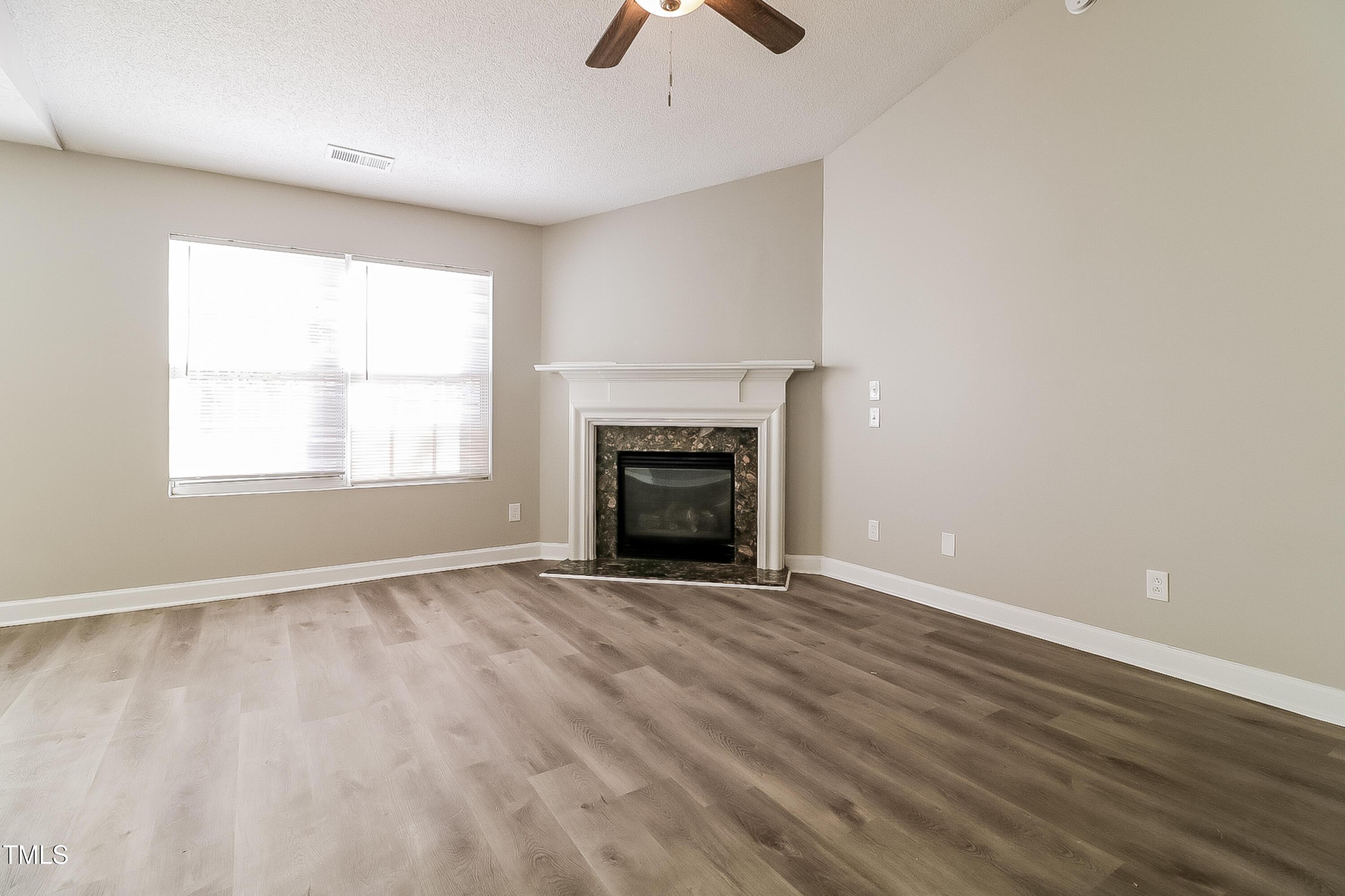 2933 Trassacks Drive Raleigh, NC 27610 - Photo 4 of 17 an empty room with ceiling fan and fireplace