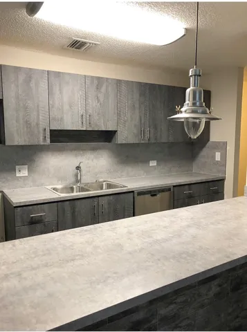 a kitchen with stainless steel appliances kitchen island a sink dishwasher a stove and black cabinets with wooden floor