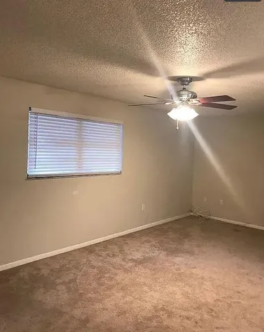 an empty room with a chandelier fan and windows