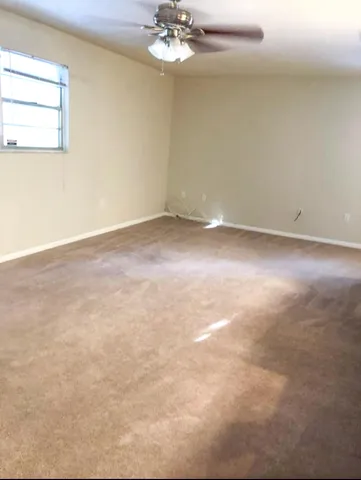 an empty room with a chandelier fan and windows
