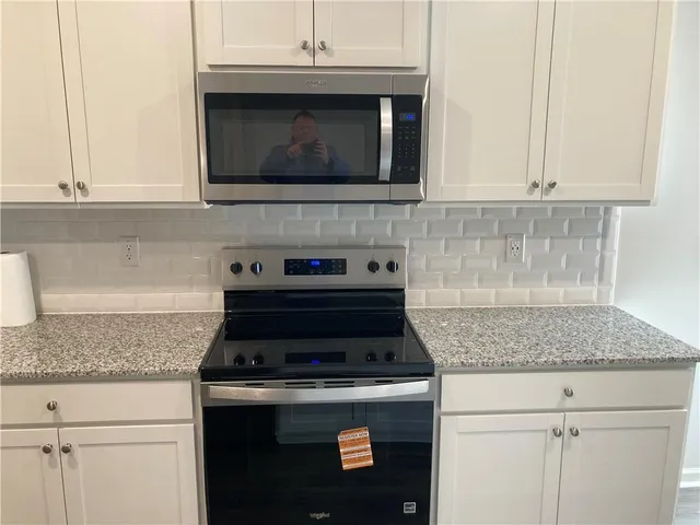 a kitchen with granite countertop white cabinets and stainless steel appliances