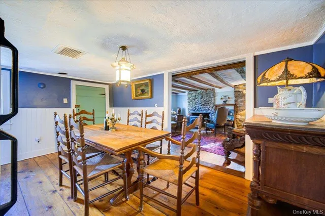 a view of a dining room and livingroom with furniture wooden floor a rug a painting and a chandelier