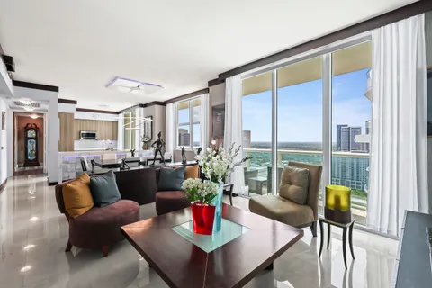 a living room with furniture kitchen view and a wooden floor
