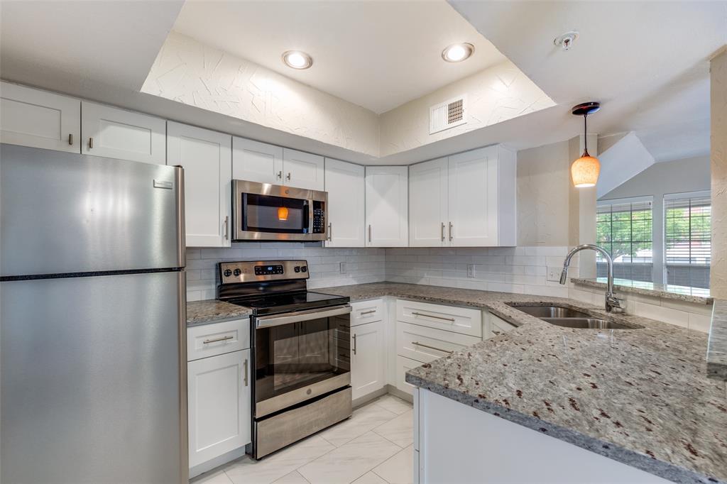 5565 Preston Oaks Road, Unit 237 Dallas, TX 75254 - Photo 2 of 14 a kitchen with granite countertop a refrigerator stove and microwave