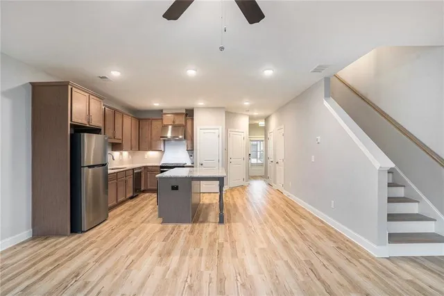 a kitchen with stainless steel appliances a refrigerator a sink dishwasher and a stove with wooden floor