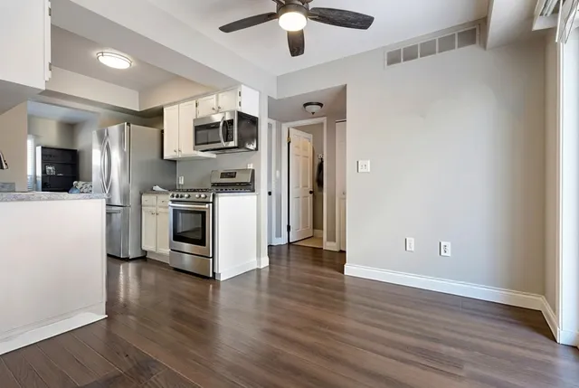 a kitchen with stainless steel appliances wooden floor and a refrigerator