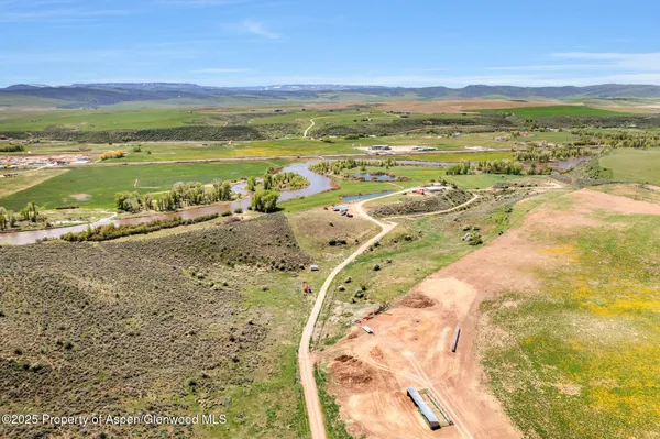 a view of a white house next to a yard with a large tree