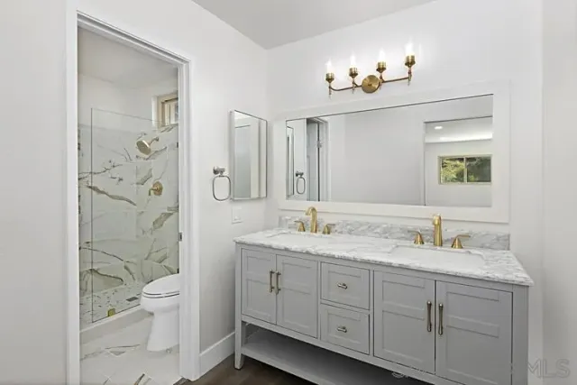 a bathroom with a granite countertop sink a toilet and a mirror