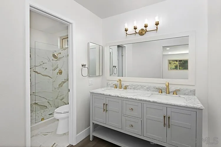 4334 Corral Canyon Road Bonita, CA 91902 - Photo 5 of 32 a spacious bathroom with a granite countertop toilet a sink a light fixture and a mirror