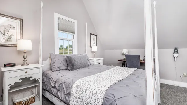 a bedroom with a bed and a lamp on dresser