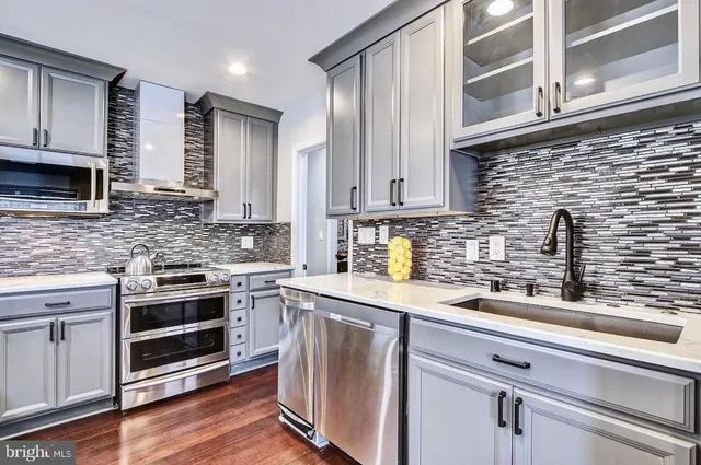 a kitchen with stainless steel appliances granite countertop a sink a stove and cabinets