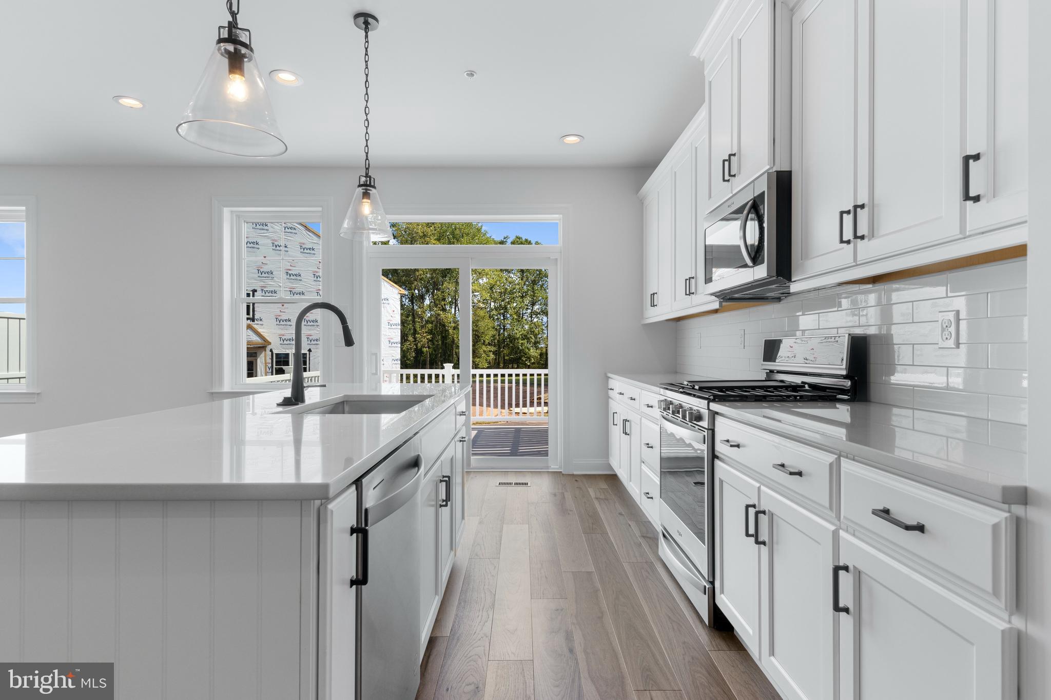 a kitchen with white cabinets a sink dishwasher and a stove with wooden floor