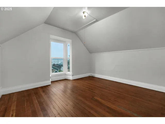 a view of an empty room with wooden floor and windows