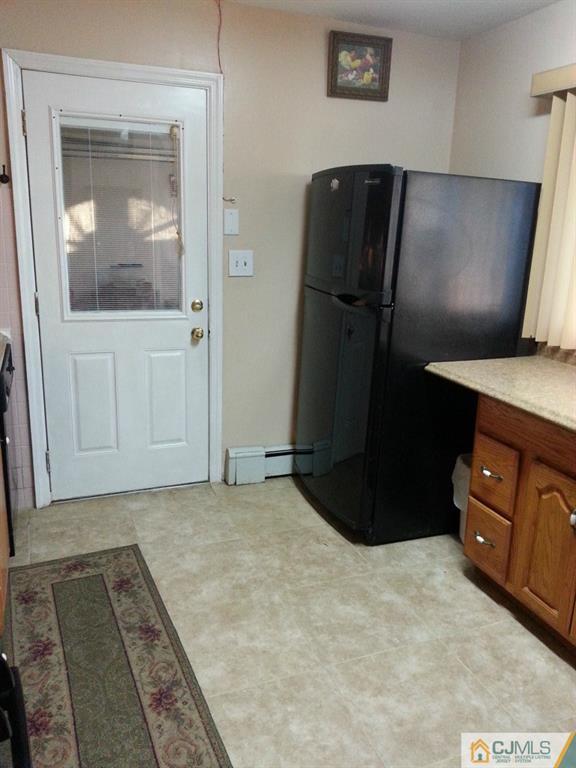 26 Winthrop Road Edison, NJ 08817 - Photo 20 of 25 a view of a refrigerator in kitchen and an empty room with wooden floor