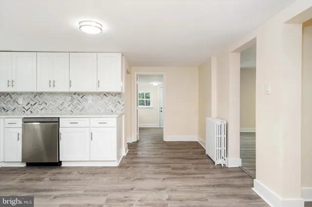 a view of a kitchen with white cabinets and wooden floor