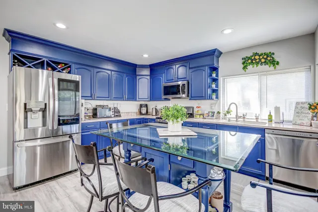 a kitchen with stainless steel appliances granite countertop a refrigerator a stove a sink a microwave and chairs