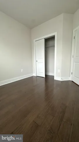 a view of an empty room with wooden floor and closet