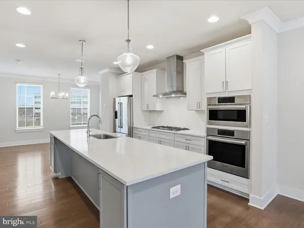a large kitchen with kitchen island a stove a sink a center island and wooden floor