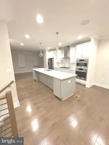 a large kitchen with kitchen island a stove a sink dishwasher and a dining table with wooden floor