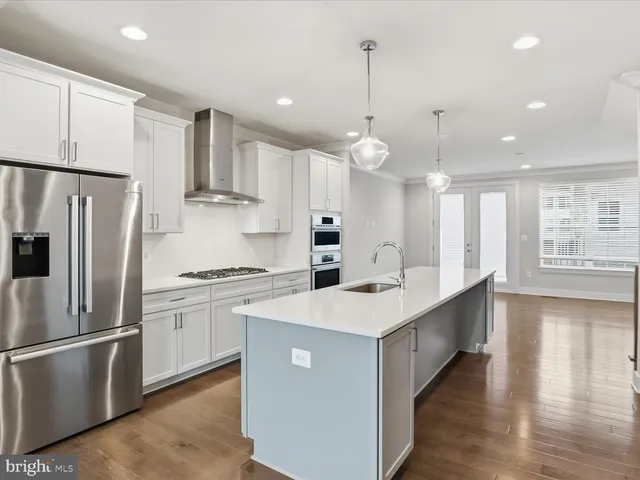 a kitchen with stainless steel appliances a refrigerator a stove a sink cabinets and wooden floor