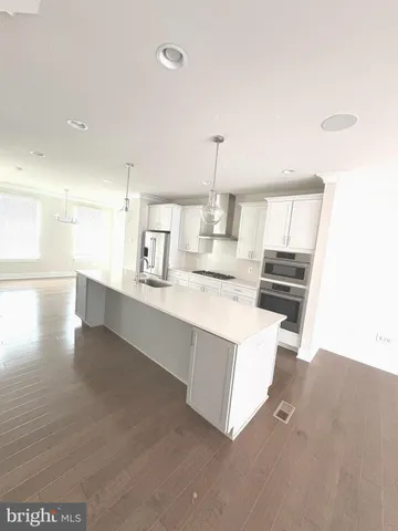 a large white kitchen with a sink and dishwasher a stove top oven with wooden floor