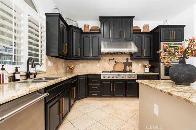 a kitchen with stainless steel appliances granite countertop a stove top oven a sink dishwasher and a refrigerator
