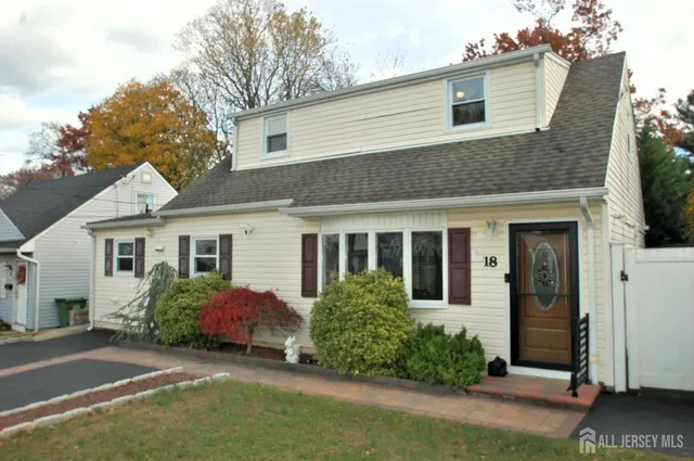 a view of a house with small yard plants and a large tree