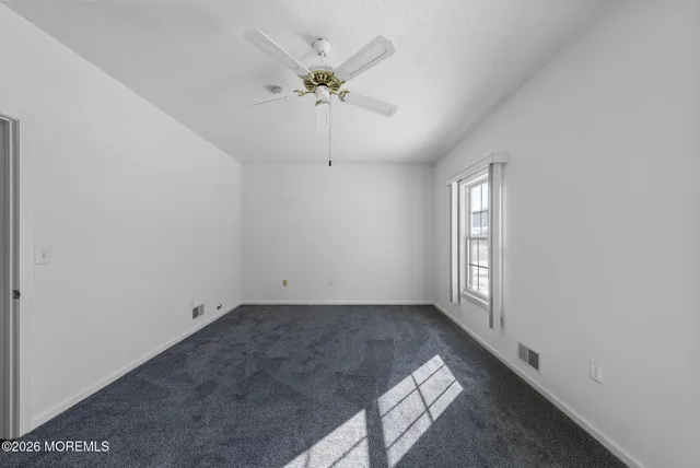 an empty room with windows and chandelier fan