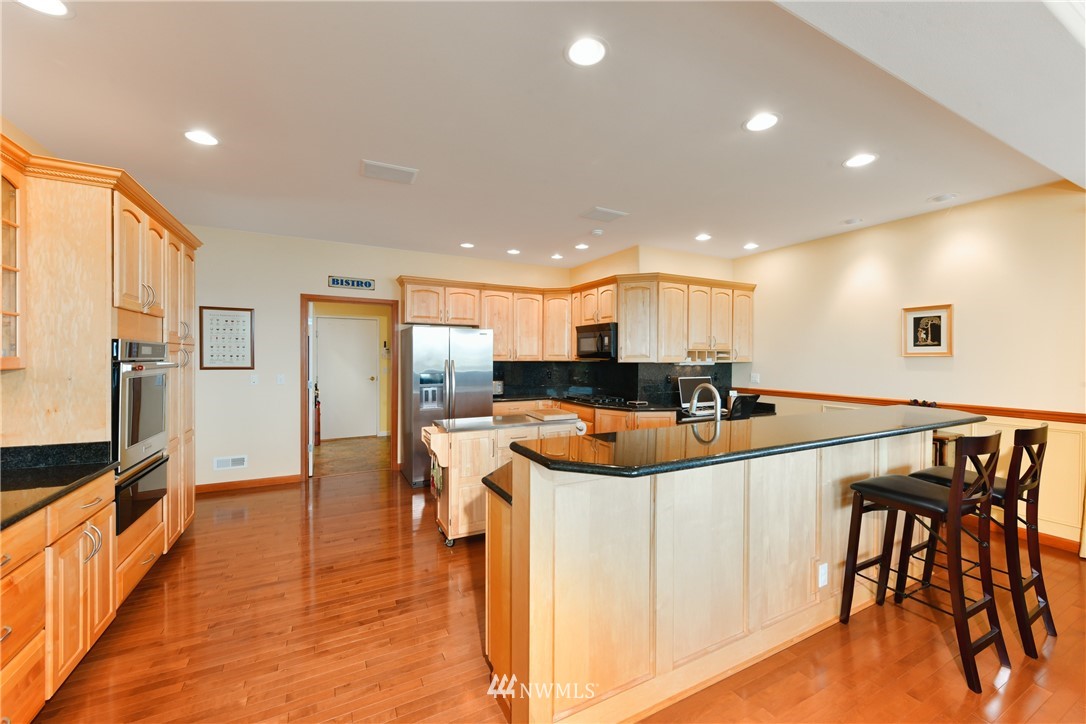 4203 Mitchell Drive Anacortes, WA 98221 - Photo 11 of 38 a kitchen with stainless steel appliances kitchen island granite countertop a table chairs and a refrigerator