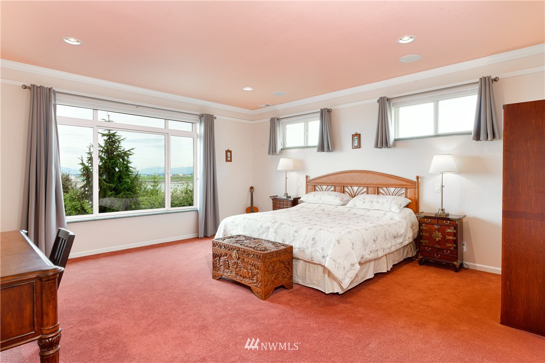 4203 Mitchell Drive Anacortes, WA 98221 - Photo 13 of 38 a spacious bedroom with a bed lamp and a large window